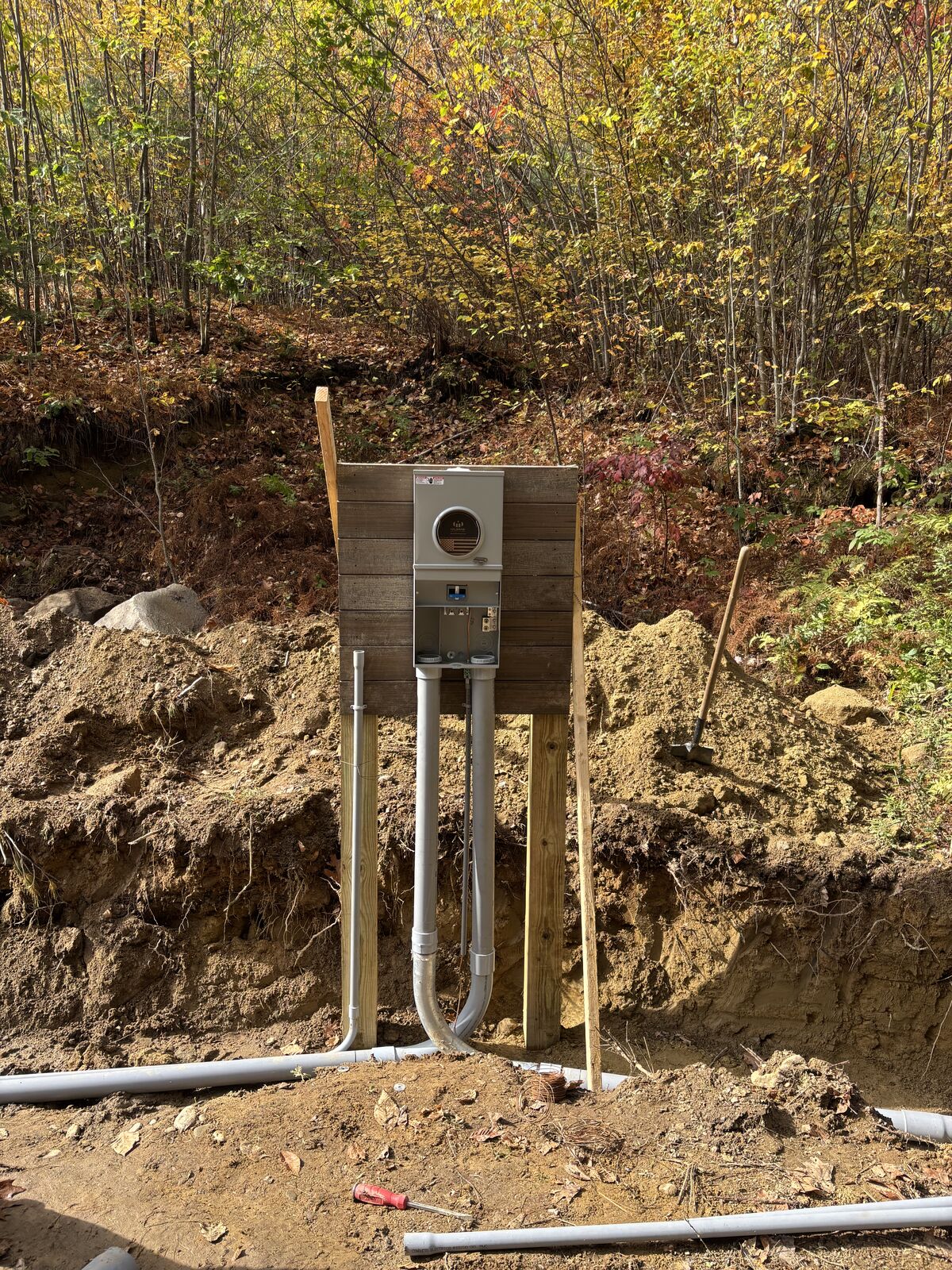 New 200 amp meter pedestal on a wood post frame with conduit stubbed up from the trench on a wooded lot in New Boston, NH