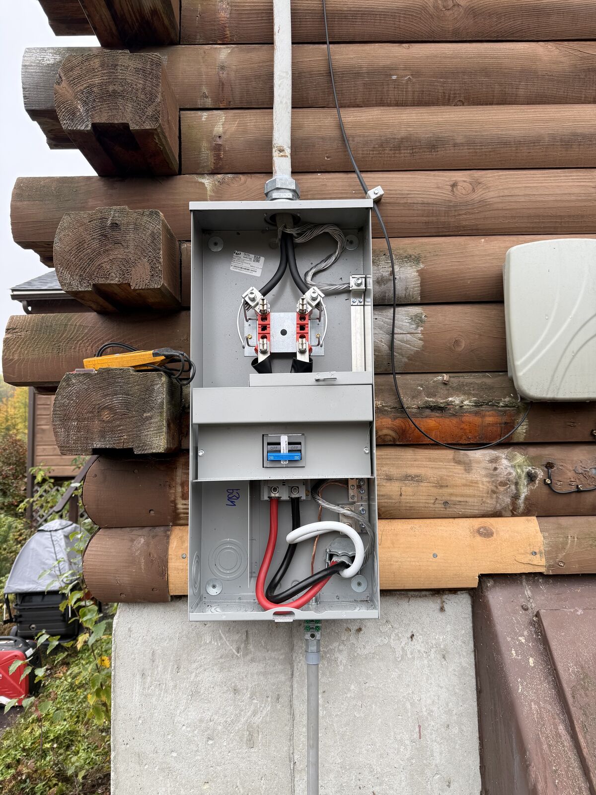 New meter socket and service conductors mounted on the side of a log home in Deering, NH