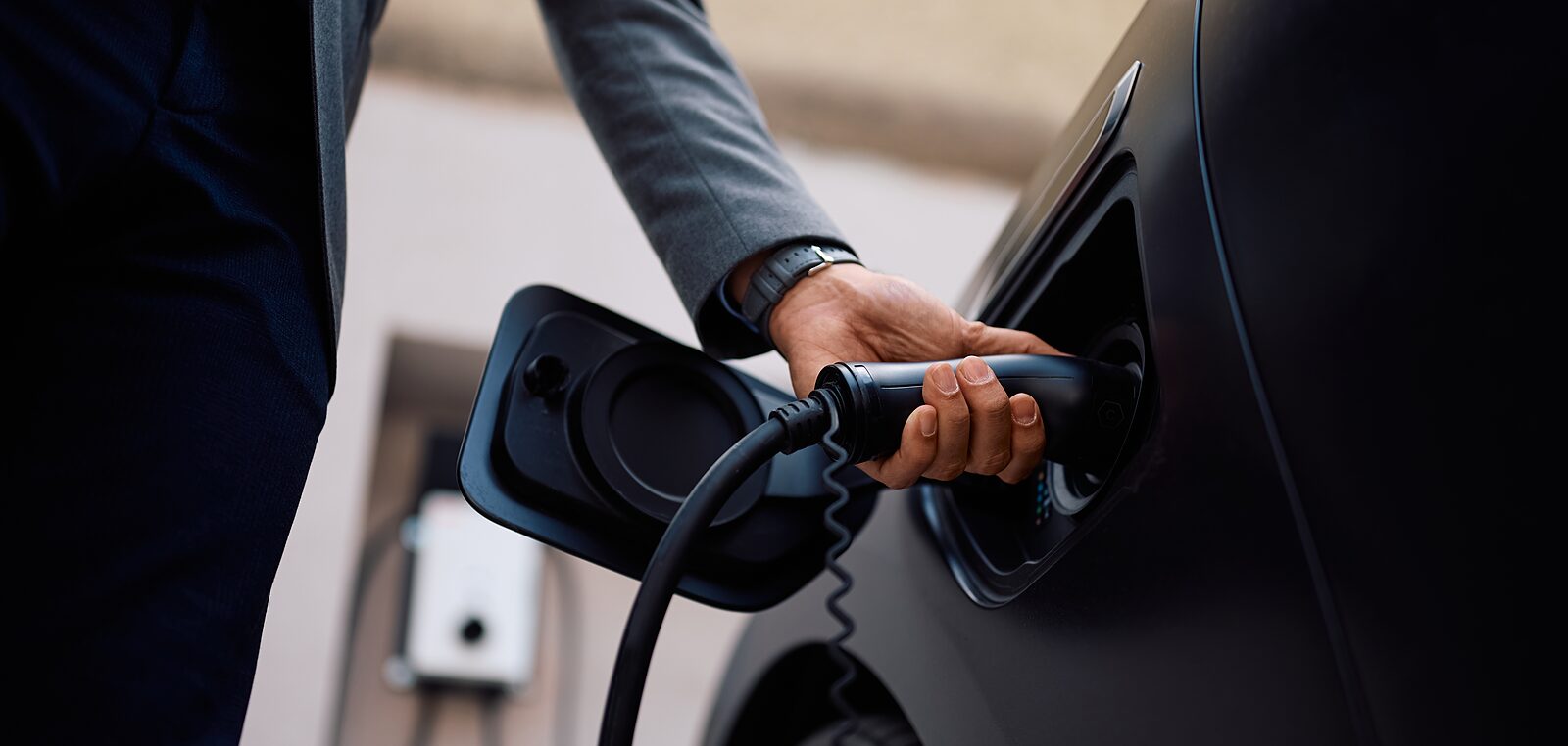 A driver plugging a charging connector into an electric car