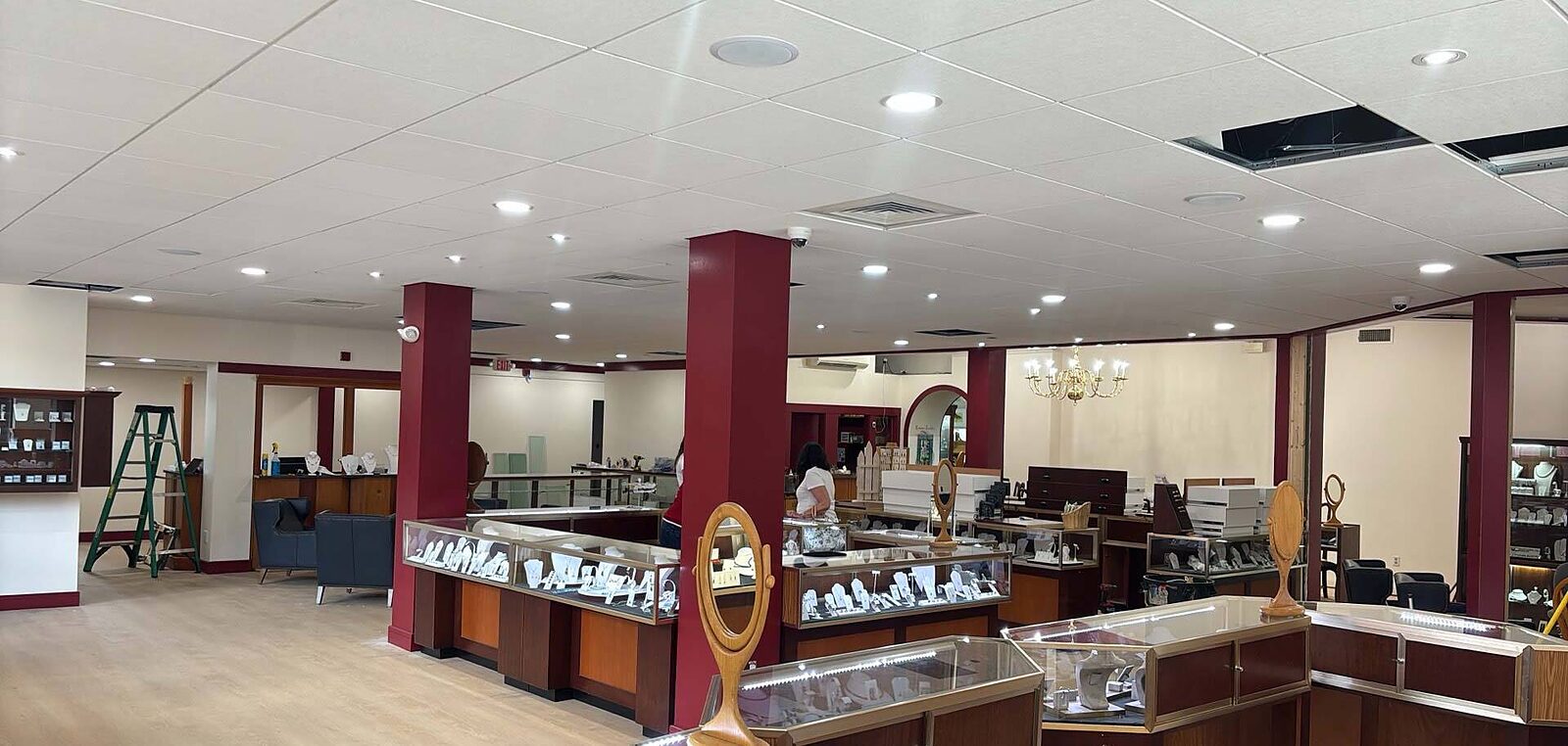 Finished retail fit-up with recessed lighting across a new ceiling grid and lit display cases below