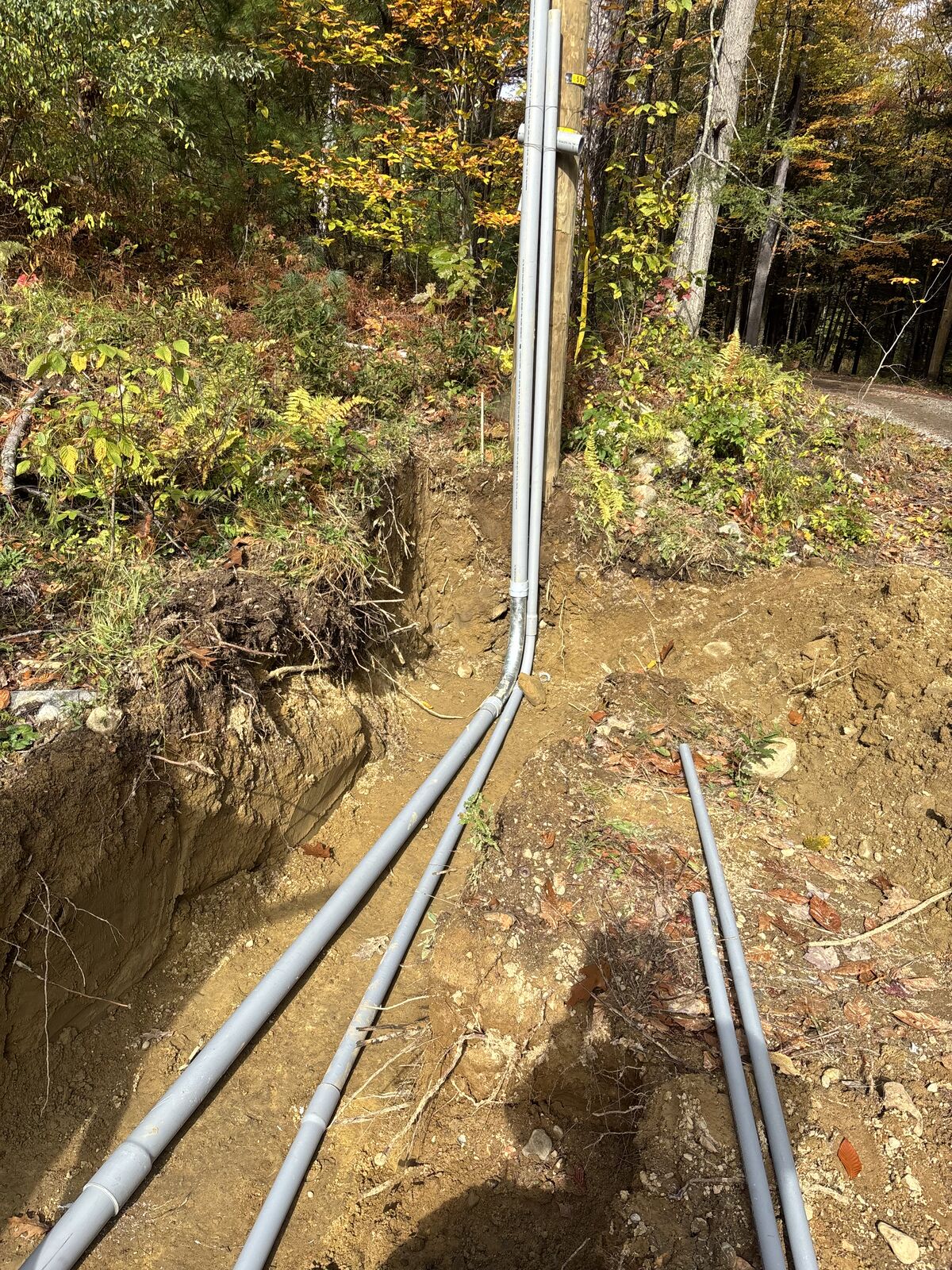 Conduit sweeps leaving the base of the utility pole and running down into the service trench