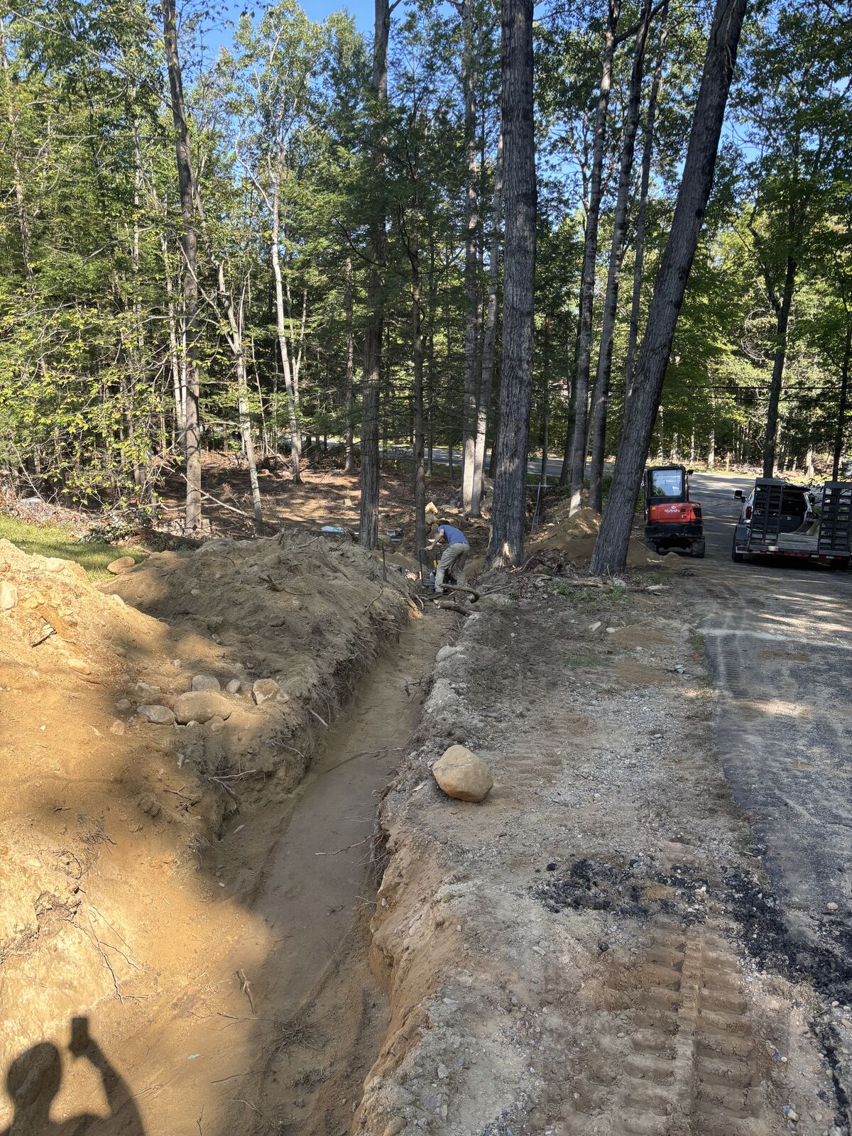 Long underground service trench cut through a wooded lot